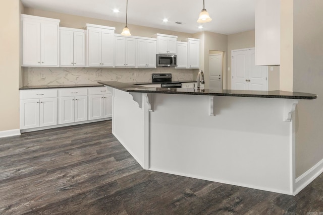 kitchen featuring appliances with stainless steel finishes, dark hardwood / wood-style floors, white cabinetry, and pendant lighting