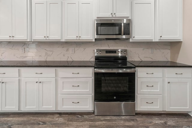 kitchen featuring decorative backsplash, white cabinetry, stainless steel appliances, and dark stone counters