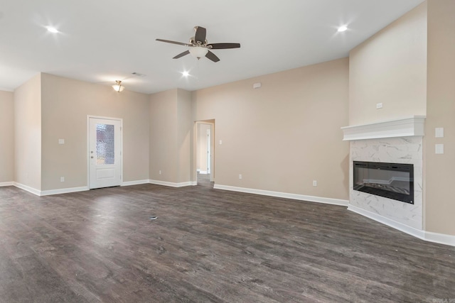 unfurnished living room with ceiling fan, a fireplace, and dark wood-type flooring