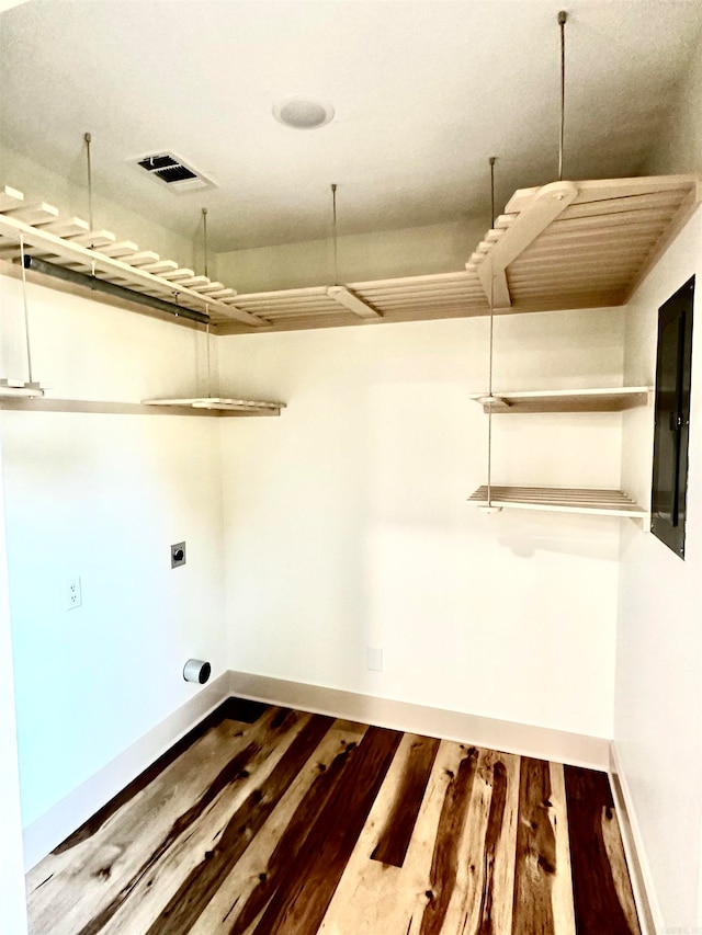 washroom with electric panel, wood-type flooring, and electric dryer hookup