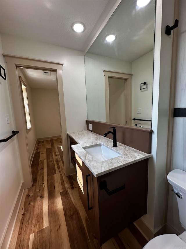 bathroom with hardwood / wood-style flooring, vanity, toilet, and a textured ceiling