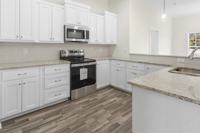 kitchen with appliances with stainless steel finishes, white cabinetry, hanging light fixtures, and sink