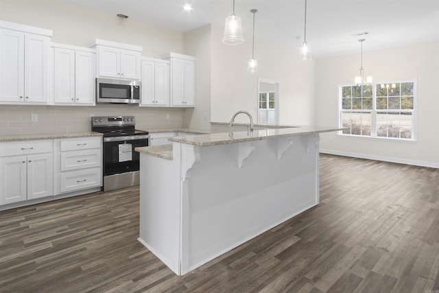 kitchen with appliances with stainless steel finishes, decorative light fixtures, and white cabinetry