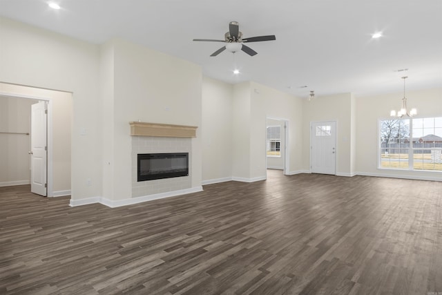 unfurnished living room with dark hardwood / wood-style floors, ceiling fan with notable chandelier, and a brick fireplace