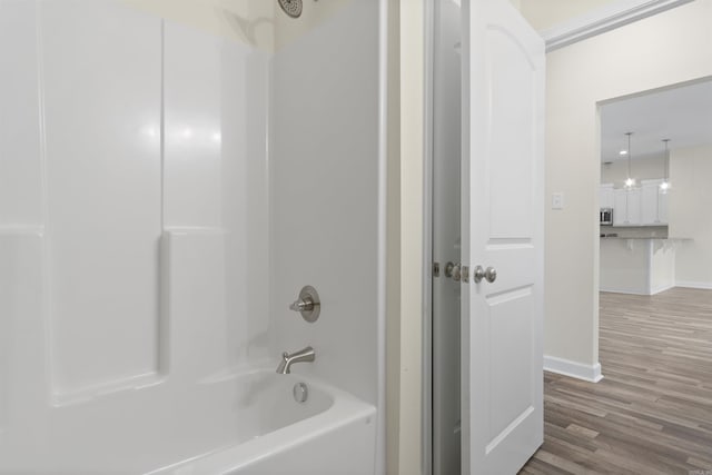 bathroom with washtub / shower combination and hardwood / wood-style flooring