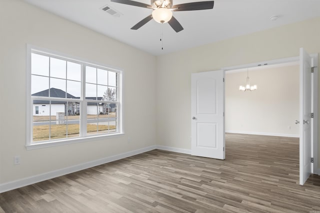 spare room featuring hardwood / wood-style floors and ceiling fan with notable chandelier