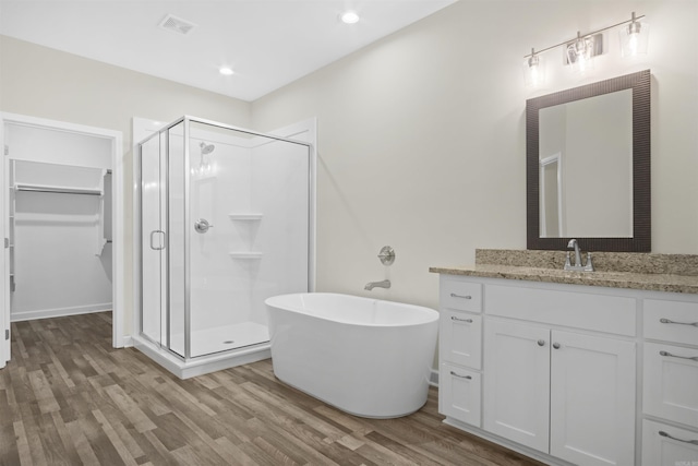 bathroom with hardwood / wood-style flooring, vanity, and plus walk in shower