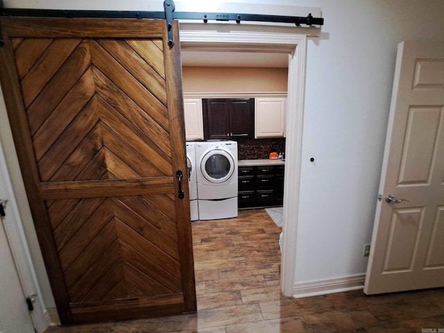 washroom with washer and dryer, a barn door, hardwood / wood-style floors, and cabinets