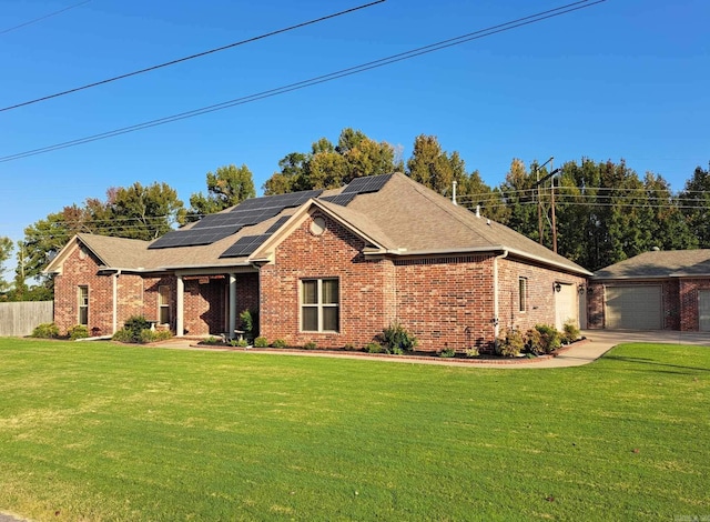 view of front of home with a garage, solar panels, and a front lawn