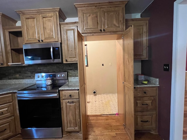 kitchen with stone countertops, ornamental molding, stainless steel appliances, decorative backsplash, and light hardwood / wood-style flooring