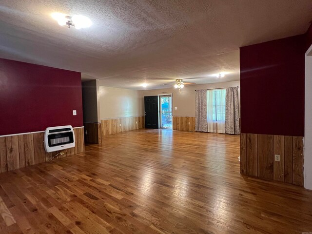 unfurnished room with a textured ceiling, wood-type flooring, and heating unit