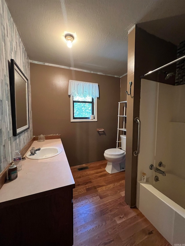 full bathroom with shower / tub combination, a textured ceiling, hardwood / wood-style flooring, toilet, and vanity