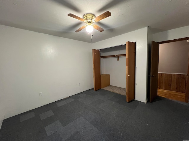 unfurnished bedroom featuring a closet, ceiling fan, and wood walls