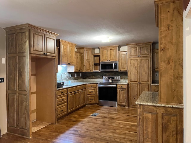 kitchen featuring tasteful backsplash, appliances with stainless steel finishes, a textured ceiling, dark hardwood / wood-style floors, and sink