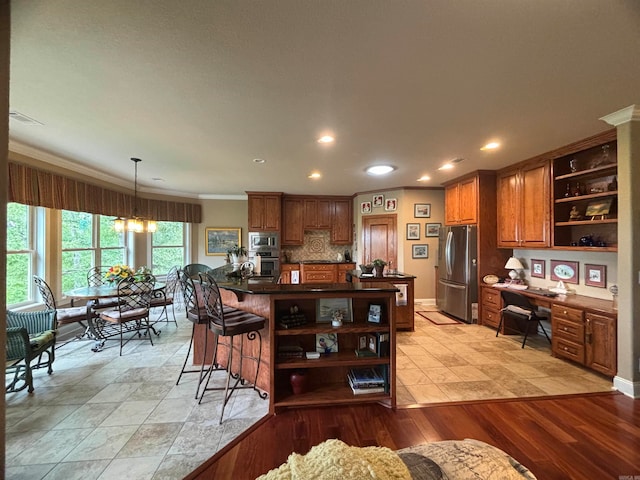 kitchen featuring light hardwood / wood-style flooring, built in desk, stainless steel appliances, crown molding, and decorative backsplash