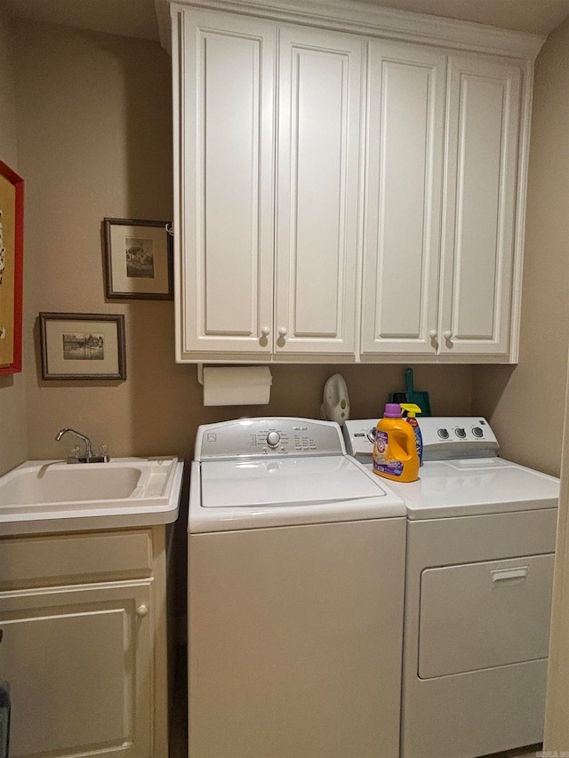 clothes washing area with washer and clothes dryer, sink, and cabinets