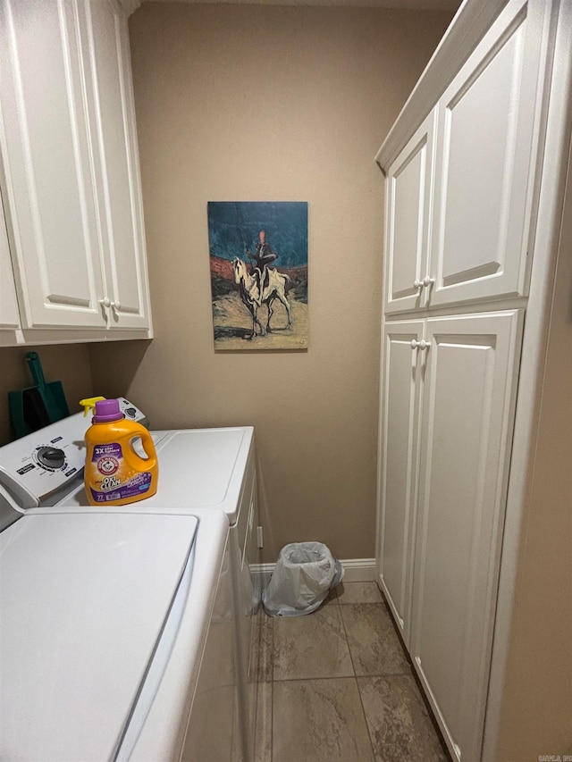 clothes washing area featuring separate washer and dryer and cabinets