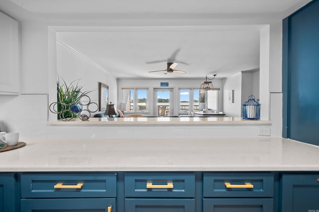 kitchen featuring blue cabinetry, light stone counters, decorative backsplash, and ceiling fan