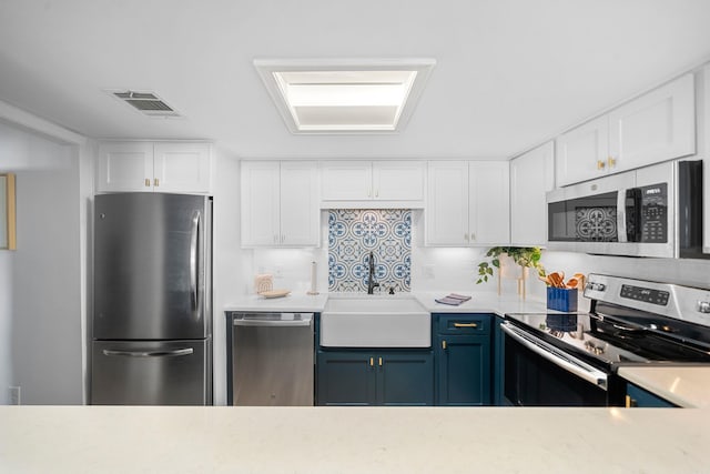 kitchen featuring decorative backsplash, white cabinets, appliances with stainless steel finishes, and blue cabinets