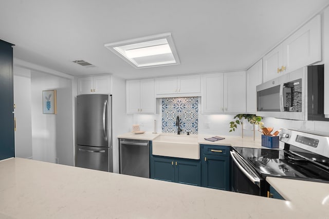 kitchen with appliances with stainless steel finishes, white cabinetry, sink, and blue cabinetry