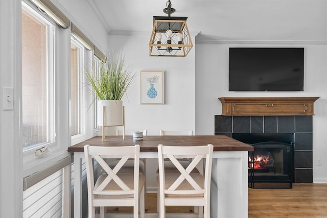 dining area with ornamental molding, hardwood / wood-style flooring, and a fireplace