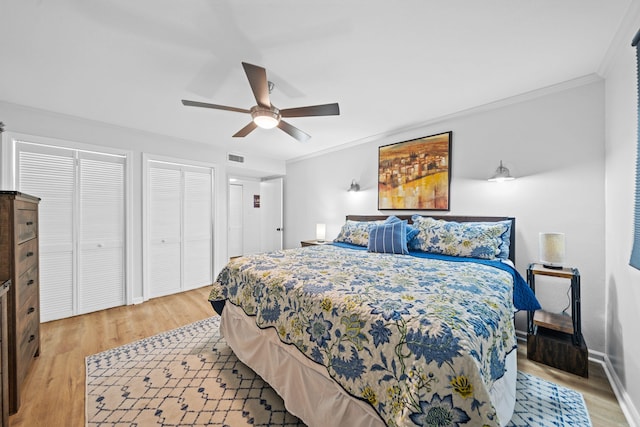 bedroom featuring ceiling fan, light hardwood / wood-style flooring, two closets, and ornamental molding