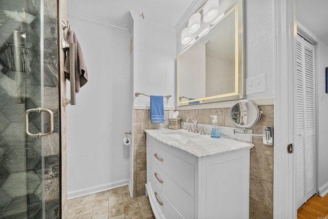 bathroom with crown molding, a shower with door, vanity, and tile walls