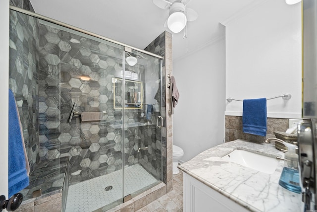 bathroom with ceiling fan, toilet, ornamental molding, a shower with door, and vanity