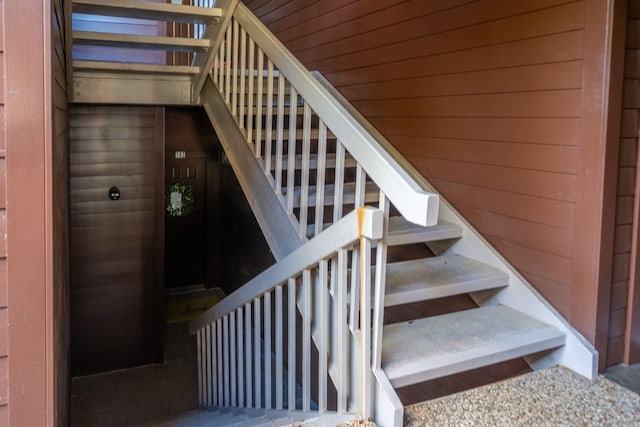 staircase featuring wood ceiling and wood walls