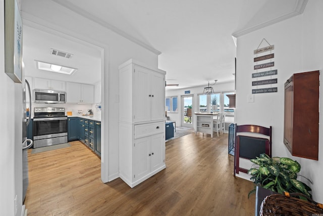 kitchen featuring white cabinets, appliances with stainless steel finishes, light wood-type flooring, and blue cabinetry