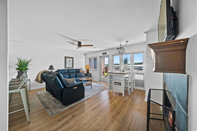 living room featuring ceiling fan with notable chandelier and light wood-type flooring