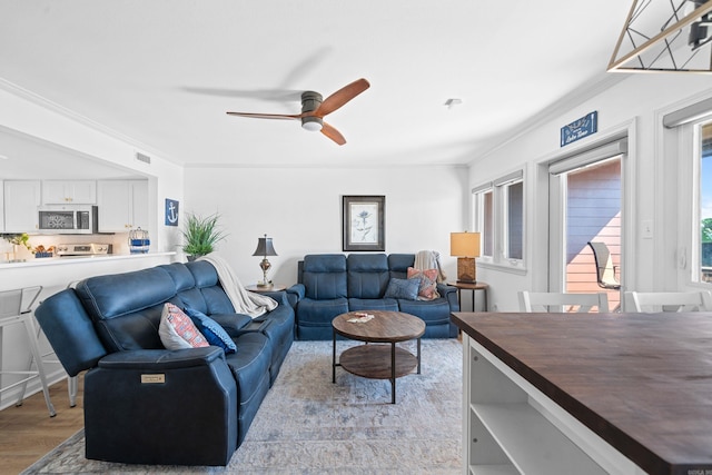 living room with crown molding, light wood-type flooring, and ceiling fan