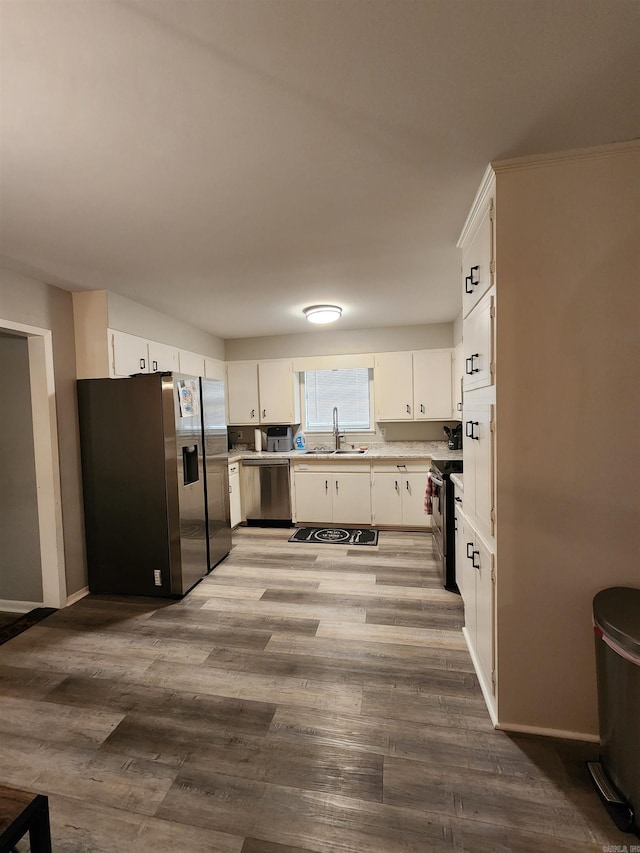 kitchen with wood-type flooring, white cabinetry, sink, and stainless steel appliances