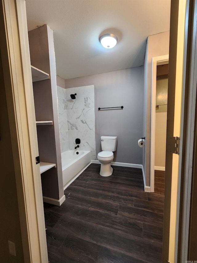 bathroom with hardwood / wood-style flooring, bathing tub / shower combination, and toilet