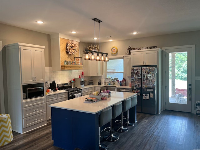 kitchen with a breakfast bar area, a kitchen island, dark hardwood / wood-style flooring, stainless steel appliances, and hanging light fixtures