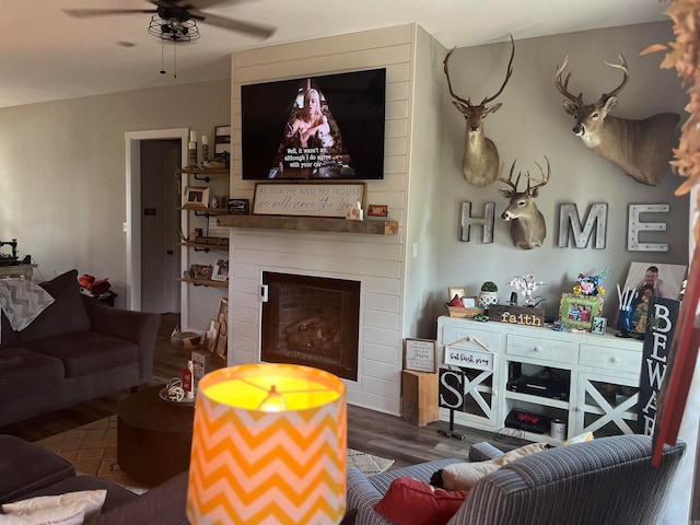 living room featuring ceiling fan, hardwood / wood-style floors, and a large fireplace