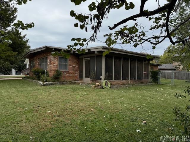 back of house with a sunroom and a lawn