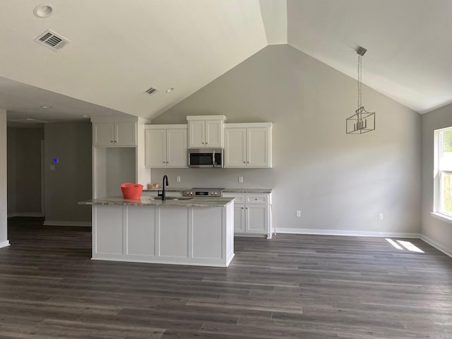 kitchen featuring pendant lighting, dark wood-type flooring, a center island with sink, stainless steel appliances, and white cabinetry