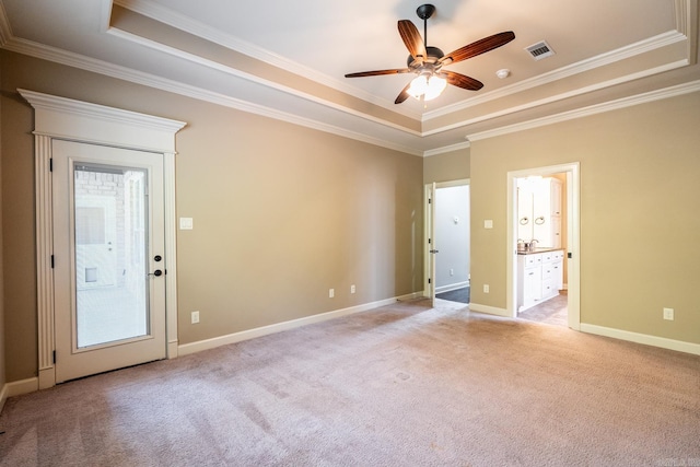 carpeted empty room with ceiling fan, crown molding, and a tray ceiling