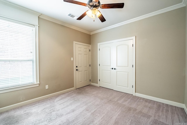 unfurnished bedroom with ceiling fan, crown molding, light carpet, and multiple windows