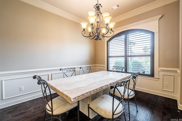 dining area with dark wood-type flooring, ornamental molding, and an inviting chandelier