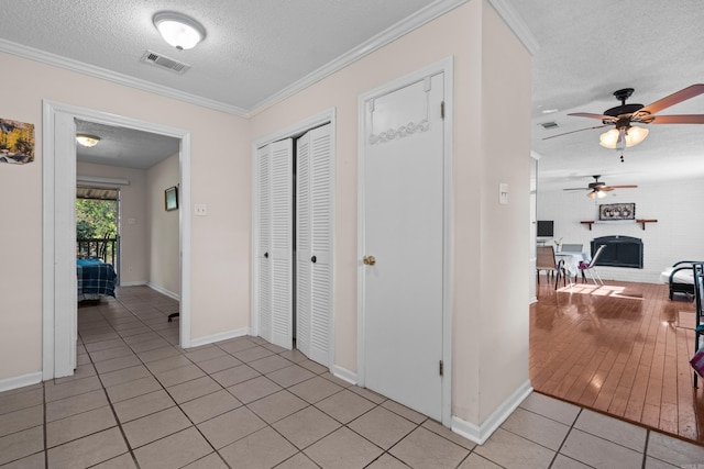 hallway featuring a textured ceiling, crown molding, and light hardwood / wood-style flooring