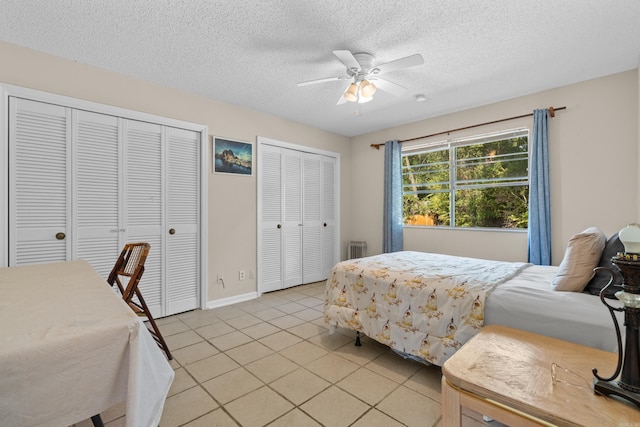 bedroom with ceiling fan, light tile patterned floors, radiator heating unit, a textured ceiling, and two closets