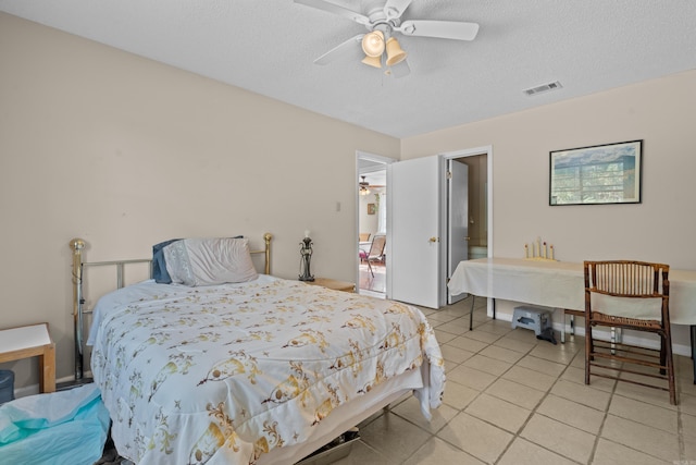 tiled bedroom with ceiling fan and a textured ceiling