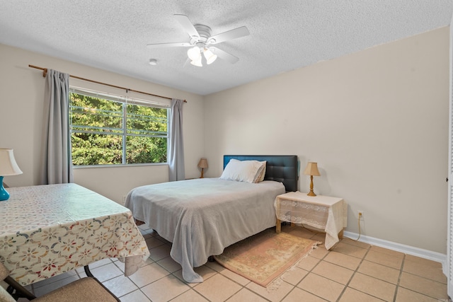 bedroom with baseboards, a ceiling fan, a textured ceiling, and light tile patterned floors