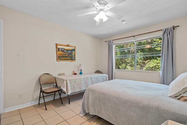bedroom featuring baseboards, a ceiling fan, a textured ceiling, and light tile patterned floors