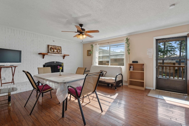 dining space featuring ceiling fan, hardwood / wood-style flooring, a fireplace, and a textured ceiling