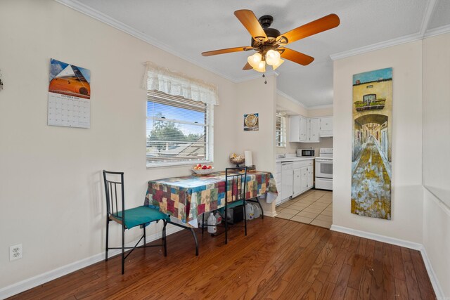 dining room featuring baseboards, ornamental molding, light wood-style flooring, and ceiling fan