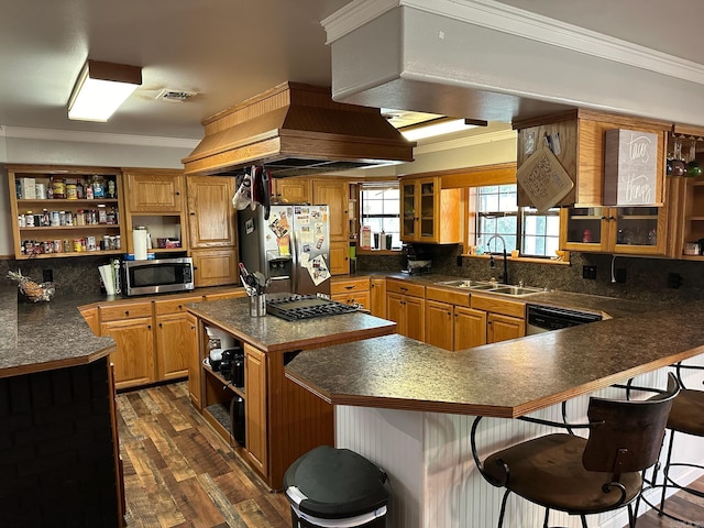 kitchen with stainless steel appliances, ornamental molding, sink, and a kitchen breakfast bar