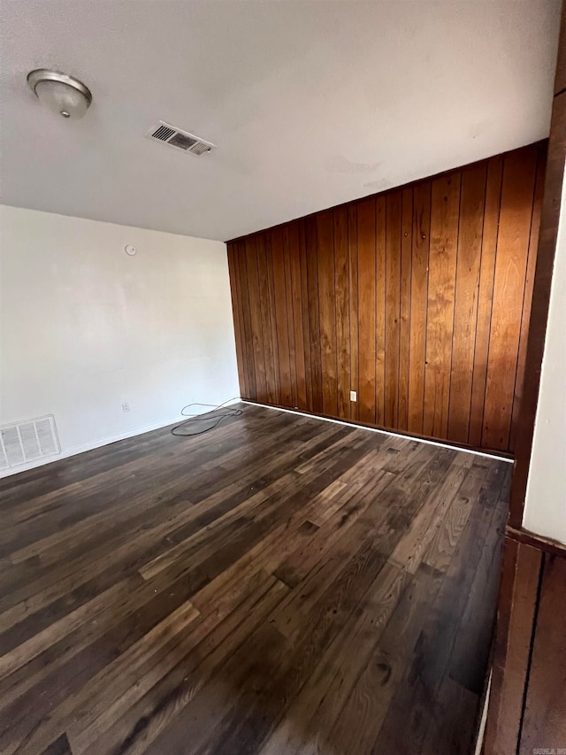 spare room featuring dark wood-type flooring and wooden walls